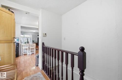 Hallway with light wood finished floors, an upstairs landing, and a textured ceiling - 9705 87 Avenue, Edmonton, AB - Indoor Photo Showing Other Room