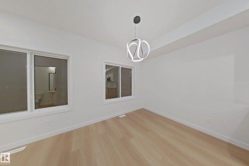 Spare room with wood finished floors and a chandelier - 65 18120 28 Avenue, Edmonton, AB - Indoor Photo Showing Other Room
