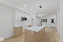 Kitchen featuring white cabinets, a center island with sink, decorative light fixtures, light wood-type flooring, and recessed lighting - 65 18120 28 Avenue, Edmonton, AB  - Indoor Photo Showing Kitchen With Double Sink 