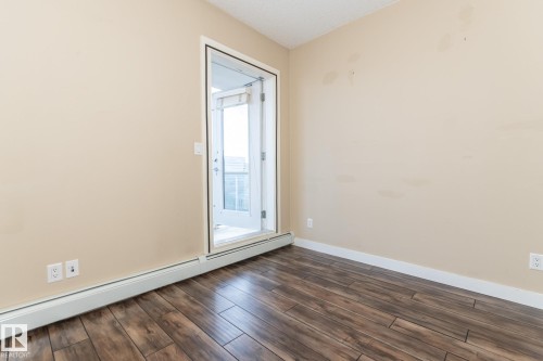 Unfurnished room featuring a baseboard radiator and dark wood-type flooring - 904 10136 104 Street Nw, Edmonton, AB - Indoor Photo Showing Other Room