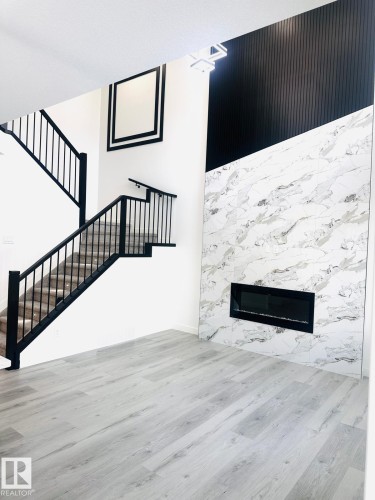 Unfurnished living room featuring wood finished floors and a high end fireplace - 3906 41 Avenue, Beaumont, AB - Indoor With Fireplace