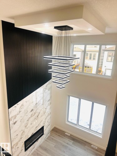 Detailed view of a textured ceiling, wood finished floors, and a glass covered fireplace - 3906 41 Avenue, Beaumont, AB - Indoor Photo Showing Other Room With Fireplace