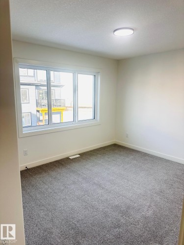Carpeted spare room featuring baseboards and a textured ceiling - 3906 41 Avenue, Beaumont, AB - Indoor Photo Showing Other Room