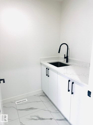Laundry area featuring a sink and light marble finish flooring - 3906 41 Avenue, Beaumont, AB - Indoor