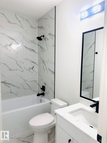 Bathroom featuring bathtub / shower combination, vanity, marble look tiles, and a textured ceiling - 3906 41 Avenue, Beaumont, AB - Indoor Photo Showing Bathroom