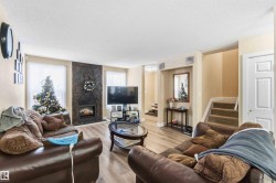 Living area featuring a large fireplace, light wood finished floors, a textured ceiling, healthy amount of natural light, and stairway - 