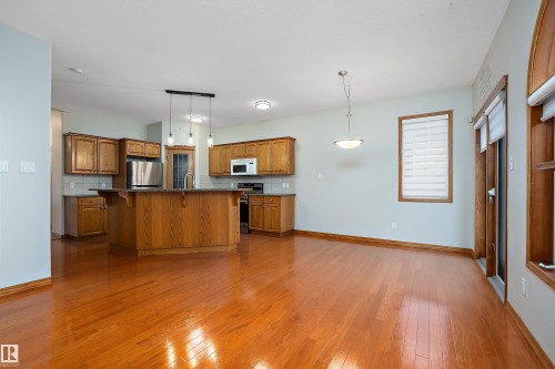Kitchen with a kitchen breakfast bar, brown cabinetry, hanging light fixtures, and a center island with sink - 4931 48 Avenue, Onoway, AB - Indoor Photo Showing Kitchen
