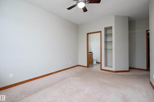Unfurnished bedroom with light colored carpet, connected bathroom, and a ceiling fan - 4931 48 Avenue, Onoway, AB - Indoor Photo Showing Other Room