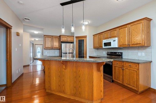 Kitchen featuring a kitchen breakfast bar, stainless steel appliances, pendant lighting, and brown cabinets - 4931 48 Avenue, Onoway, AB - Indoor Photo Showing Kitchen