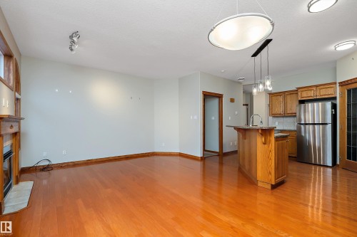 Kitchen featuring brown cabinetry, a breakfast bar, freestanding refrigerator, an island with sink, and open floor plan - 4931 48 Avenue, Onoway, AB - Indoor Photo Showing Kitchen