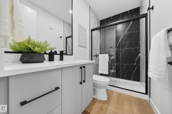 Bathroom with vanity, a marble finish shower, and light wood-type flooring - 