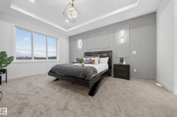 Bedroom featuring a raised ceiling, light colored carpet, and recessed lighting - 