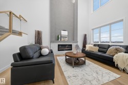 Living area featuring plenty of natural light, a fireplace, a towering ceiling, and light wood finished floors - 
