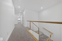 Hallway with light colored carpet, recessed lighting, and an upstairs landing - 