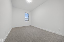 Carpeted spare room featuring vaulted ceiling and baseboards - 