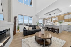 Living area with light wood-style flooring, a glass covered fireplace, and a towering ceiling - 