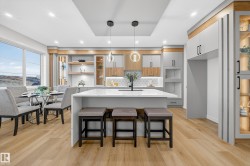 Kitchen with open shelves, pendant lighting, a kitchen bar, an island with sink, and light stone countertops - 