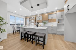 Kitchen with open shelves, modern cabinets, pendant lighting, white cabinetry, and a center island with sink - 