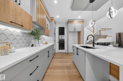 Kitchen with light stone countertops, light wood finished floors, hanging light fixtures, modern cabinets, and recessed lighting - 