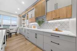 Kitchen featuring light wood finished floors, light stone countertops, open shelves, recessed lighting, and modern cabinets - 