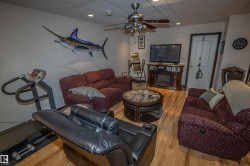 Living room with a drop ceiling, wood finished floors, ceiling fan, recessed lighting, and a glass covered fireplace - 