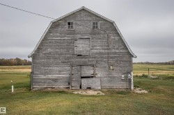 View of side of home featuring a gambrel roof, a barn, and a yard - 