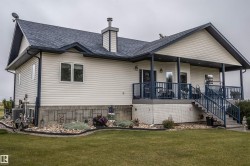 Rear view of house featuring stairs, a porch, a yard, roof with shingles, and a chimney - 