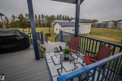 Wooden deck with a lawn, an outdoor structure, a grill, and a garage - 