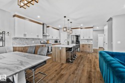 Kitchen with white cabinets, a breakfast bar area, an island with sink, pendant lighting, and tasteful backsplash - 