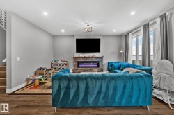 Living room with dark wood-type flooring, a stone fireplace, recessed lighting, and stairs - 