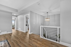 Interior space with an upstairs landing, wood finished floors, and a chandelier - 