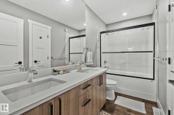Full bathroom featuring enclosed tub / shower combo, double vanity, dark wood-type flooring, and recessed lighting - 