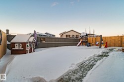 Snowy yard with a fenced backyard and a playground - 
