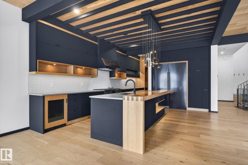 Kitchen with open shelves, modern cabinets, built in refrigerator, a center island with sink, and a wood ceiling with exposed beams - 104 Edgewater Circle, Leduc, AB - Indoor Photo Showing Kitchen