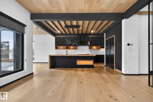 Kitchen featuring dark cabinetry, modern cabinets, backsplash, an island with sink, and a wooden ceiling with exposed beams - 104 Edgewater Circle, Leduc, AB - Indoor Photo Showing Kitchen