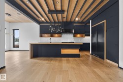 Kitchen with dark cabinets, modern cabinets, decorative backsplash, an island with sink, and paneled fridge - 
