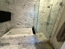Bathroom with a marble finish shower, a garden tub, marble finish floors, and tile walls - 