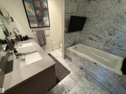 Full bathroom with light marble finish flooring, double vanity, and a garden tub - 