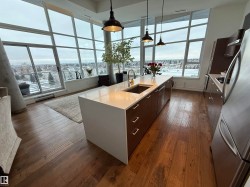 Kitchen featuring dark brown cabinetry, stainless steel appliances, dark wood-style floors, modern cabinets, and light stone countertops - 