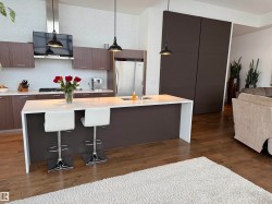 Kitchen with modern cabinets, a breakfast bar area, pendant lighting, dark wood-type flooring, and tasteful backsplash - 