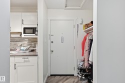 Kitchen featuring white cabinets, white microwave, light wood-style floors, tasteful backsplash, and light countertops - 