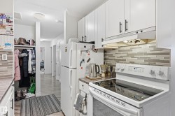 Kitchen featuring electric range, decorative backsplash, white cabinetry, under cabinet range hood, and a textured ceiling - 