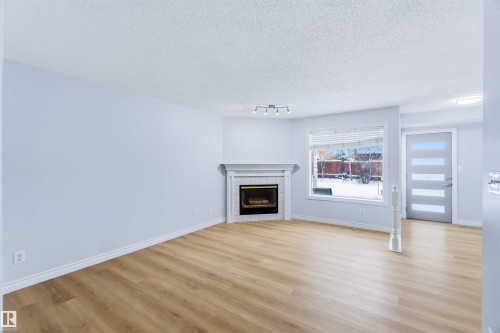 Unfurnished living room with a textured ceiling, a tile fireplace, and light wood-type flooring - 115 Deer Ridge Drive, St. Albert, AB - Indoor Photo Showing Living Room With Fireplace