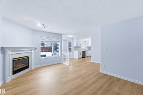 Unfurnished living room featuring a textured ceiling, light wood-style flooring, and a fireplace - 115 Deer Ridge Drive, St. Albert, AB - Indoor Photo Showing Living Room With Fireplace