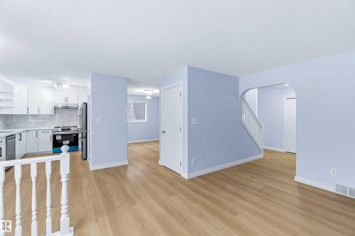 Unfurnished living room with light wood-type flooring, stairs, and arched walkways - 115 Deer Ridge Drive, St. Albert, AB - Indoor Photo Showing Kitchen