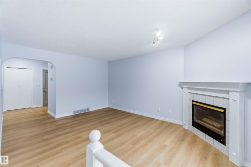 Unfurnished living room with arched walkways, a fireplace, and light wood-style flooring - 115 Deer Ridge Drive, St. Albert, AB - Indoor Photo Showing Living Room With Fireplace