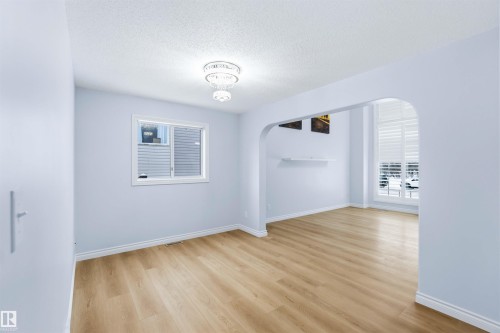 Spare room with arched walkways, a textured ceiling, light wood-style floors, and plenty of natural light - 115 Deer Ridge Drive, St. Albert, AB - Indoor Photo Showing Other Room
