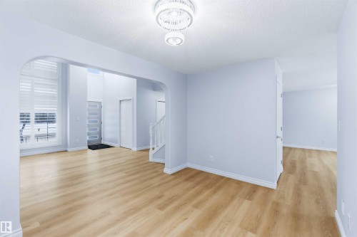 Spare room with arched walkways, a textured ceiling, stairway, and light wood finished floors - 115 Deer Ridge Drive, St. Albert, AB - Indoor Photo Showing Other Room
