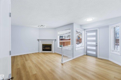 Foyer entrance with a textured ceiling, a tile fireplace, and light wood-type flooring - 115 Deer Ridge Drive, St. Albert, AB - Indoor Photo Showing Living Room With Fireplace
