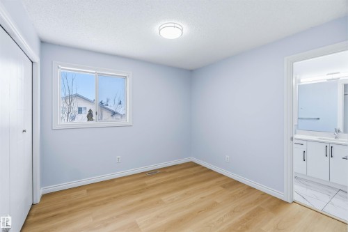 Unfurnished bedroom featuring light wood-style flooring, a textured ceiling, a closet, and ensuite bath - 115 Deer Ridge Drive, St. Albert, AB - Indoor Photo Showing Other Room